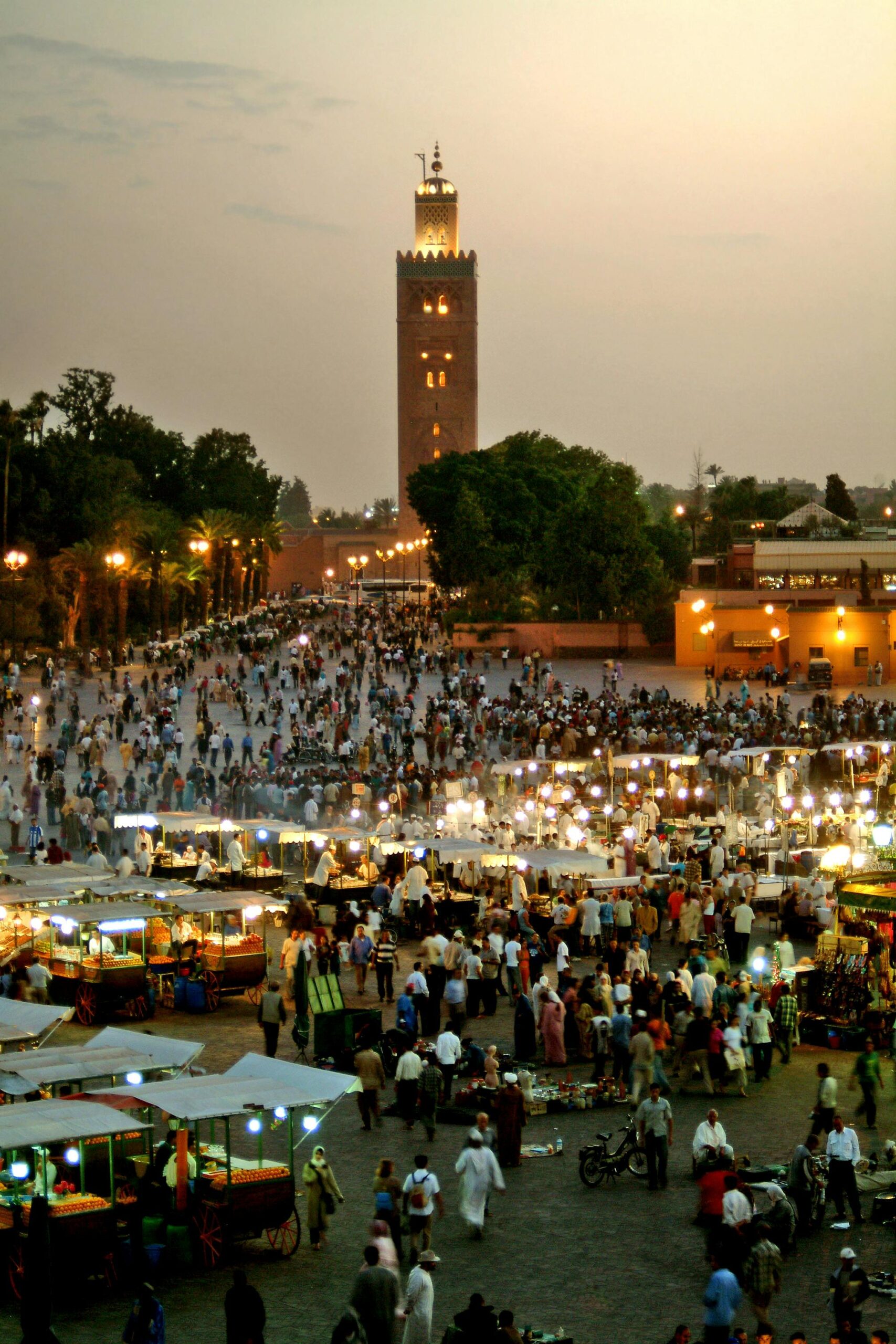 pexels-photo-15360681-15360681 Evening view of bustling Jemaa El-Fnaa market square in Marrakech, Morocco, illuminated with vibrant lights.
