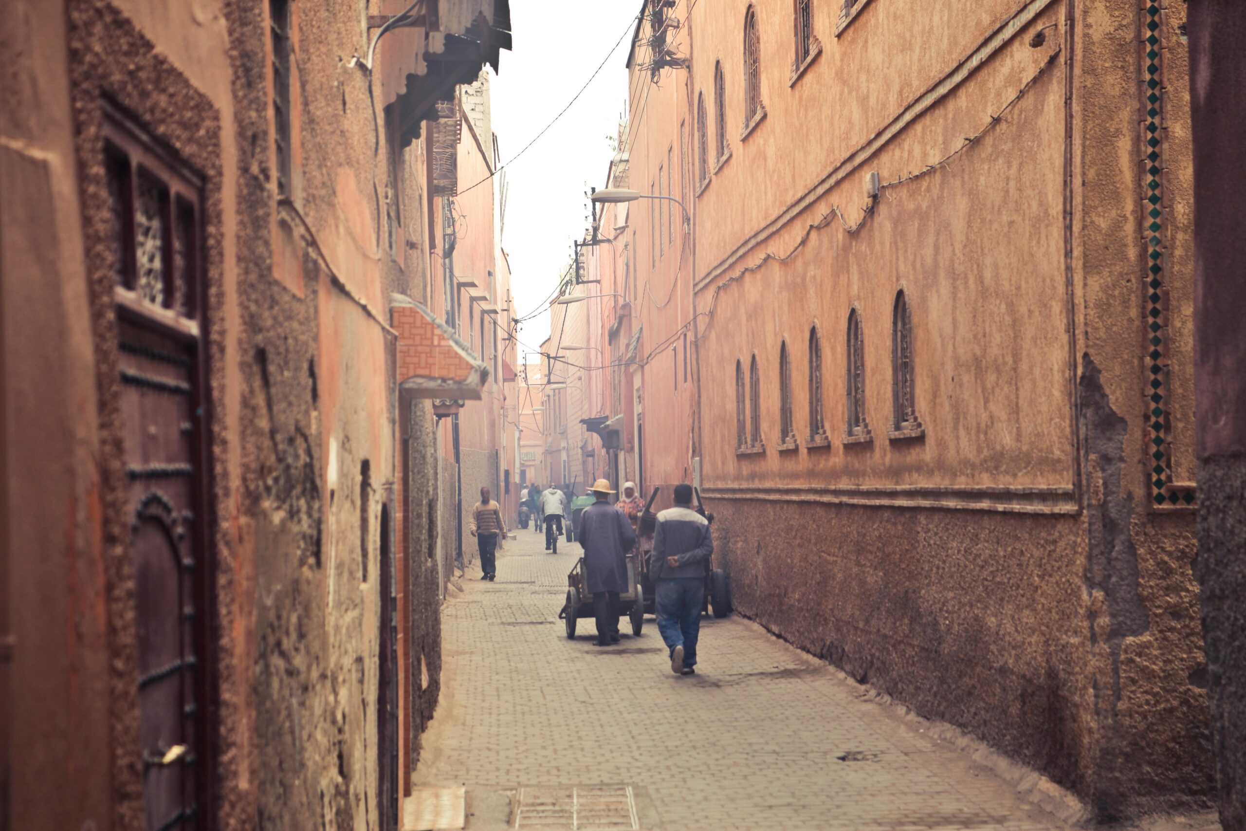 pexels-photo-3760256-3760256-1 Perspective view of aged narrow street with people walking among ancient oriental buildings in hazy light