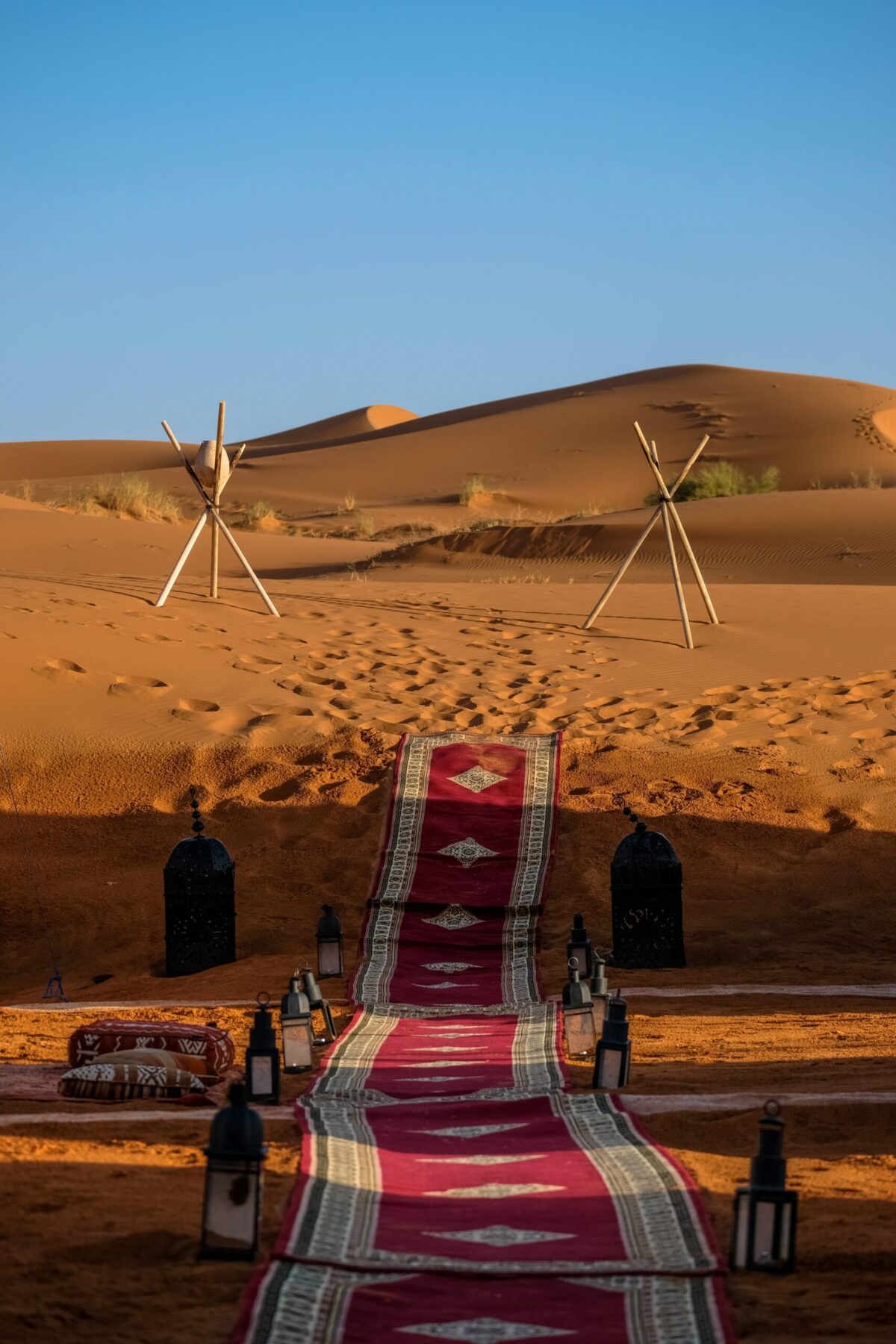 Vertical shot of a red carpet in the middle of lamps and stick tripod with a rock in the distance